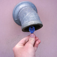 Load image into Gallery viewer, 50663 Magnetic Key, KW1-66 Blue - Hand Holding Blue Magnetic Key Next to a Metal Drain Pipe