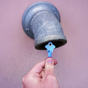 50683 Magnetic Key, SC1-68 Blue - Hand Holding Blue Magnetic Key Next to a Metal Drain Pipe