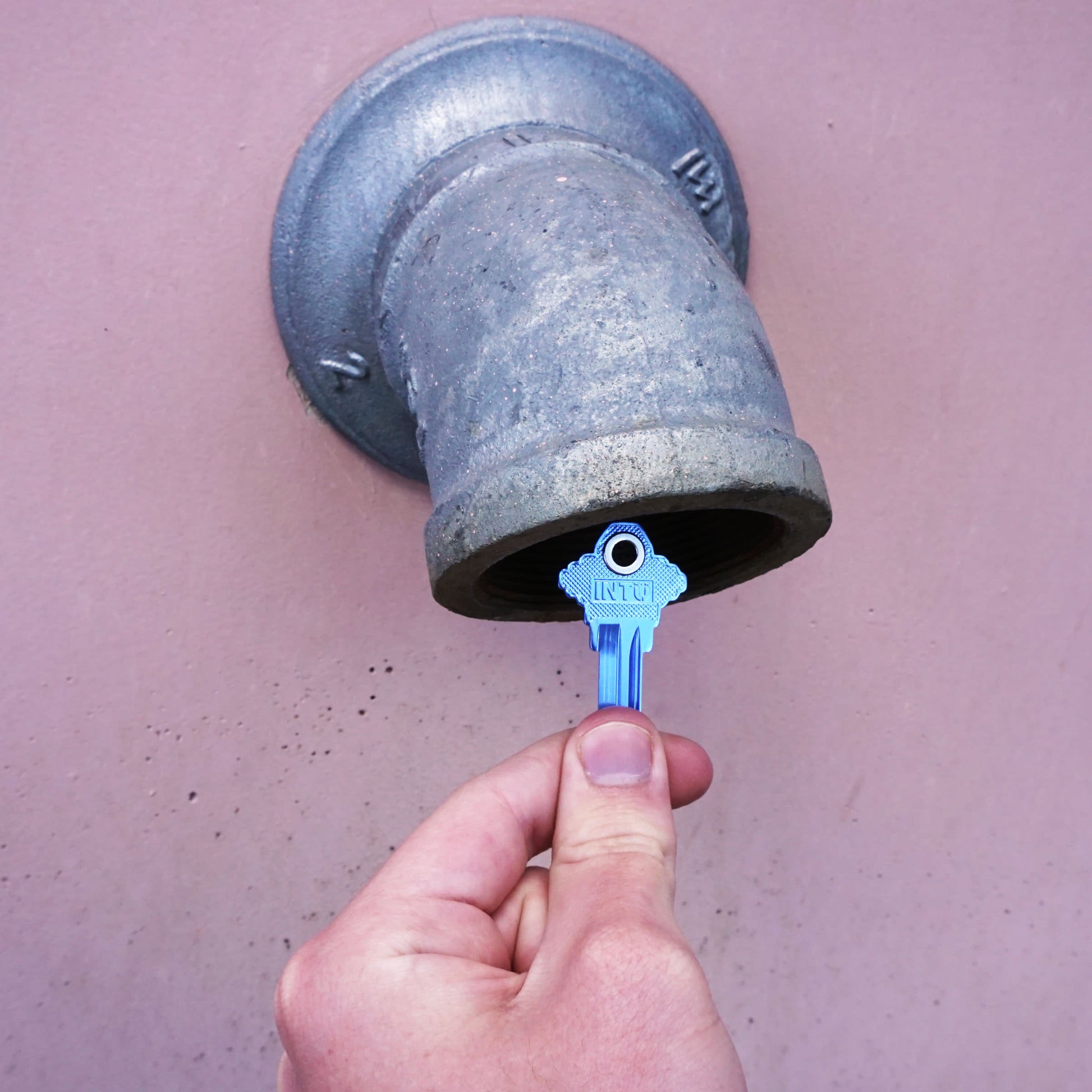 Load image into Gallery viewer, 50683 Magnetic Key, SC1-68 Blue - Hand Holding Blue Magnetic Key Next to a Metal Drain Pipe