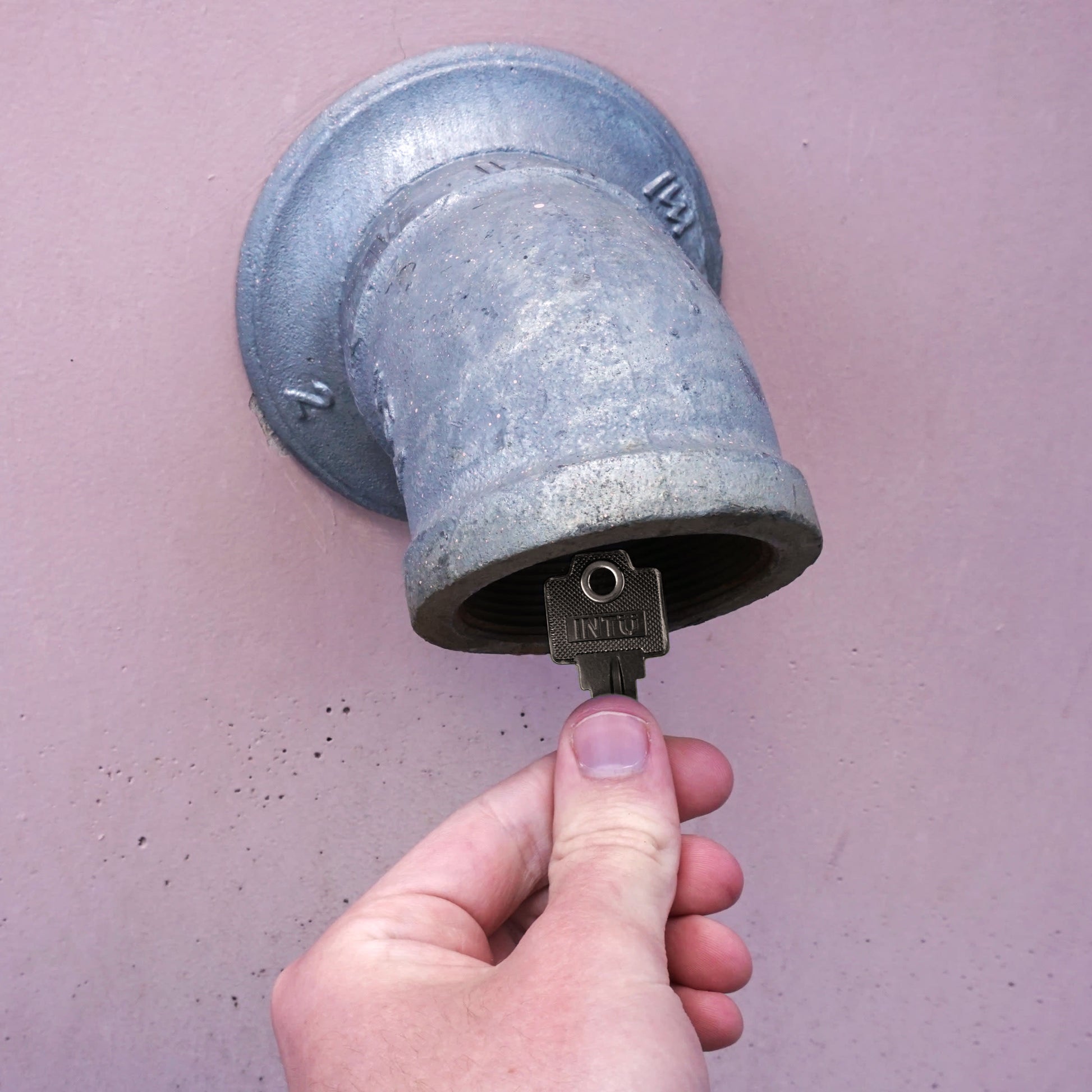 Load image into Gallery viewer, 50776 Magnetic Key, WR5-67 Black - Hand Holding Magnetic Key Next to a Drain Pipe